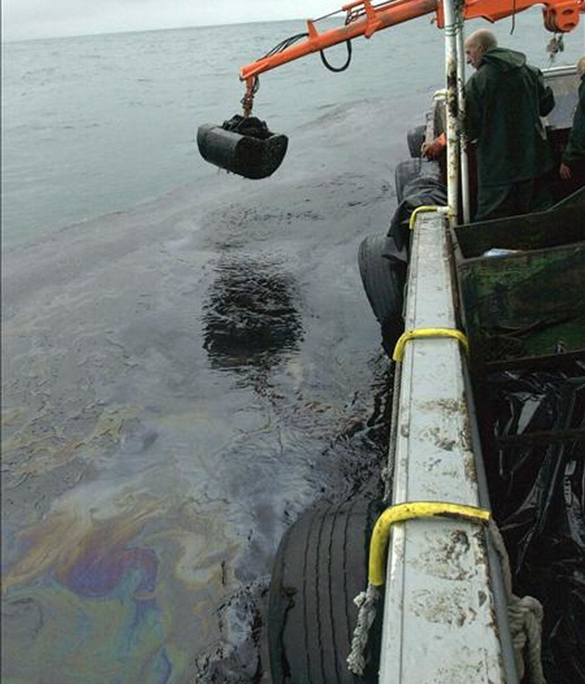 Marineros de la ría de Arosa recogen el petróleo del mar con la grúa de su barco pesquero durante la movilización para evitar que la mancha de fuel entre en la ría, tras el accidente del Prestige. EFE/Archivo
