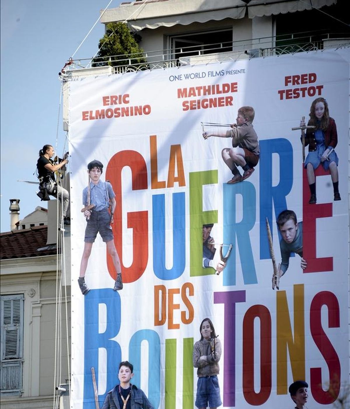 Varios operarios despliegan un enorme cartel publicitario de la cinta "La Guerre de boutons" (1962), del fallecido actor, director y productor de cine francés Yves Robert, que se presentará en el Marché du Film del Festival de Cannes (Francia), hoy, lunes 09 de mayo de 2011. EFE