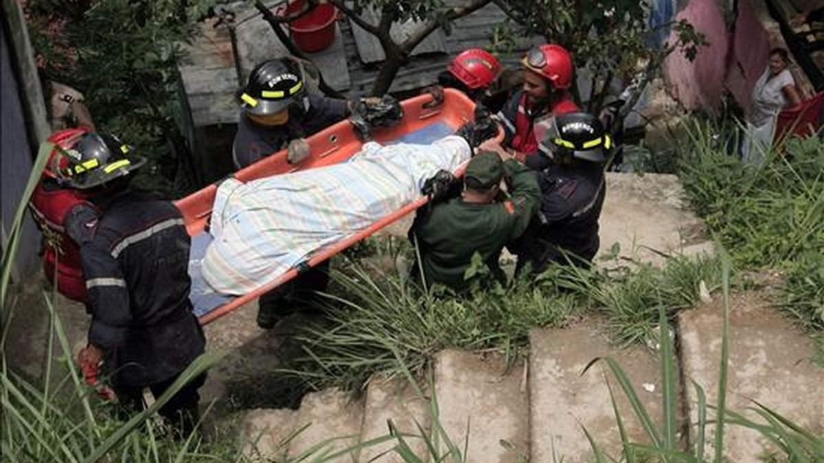 Un grupo de socorristas traslada el cuerpo de uno de los cinco de siete miembros de una misma familia que murieron sepultados bajo un deslizamiento de tierra y rocas que afectó a su vivienda en una barriada popular aledaña a Caracas (Venezuela). EFE