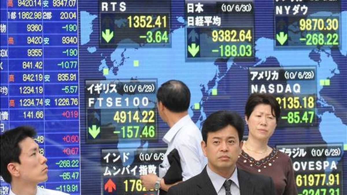 Varias personas pasan por delante de un monitor en el que se muestran las variaciones del índice Nikkei, en Tokio (Japón). EFE/Archivo