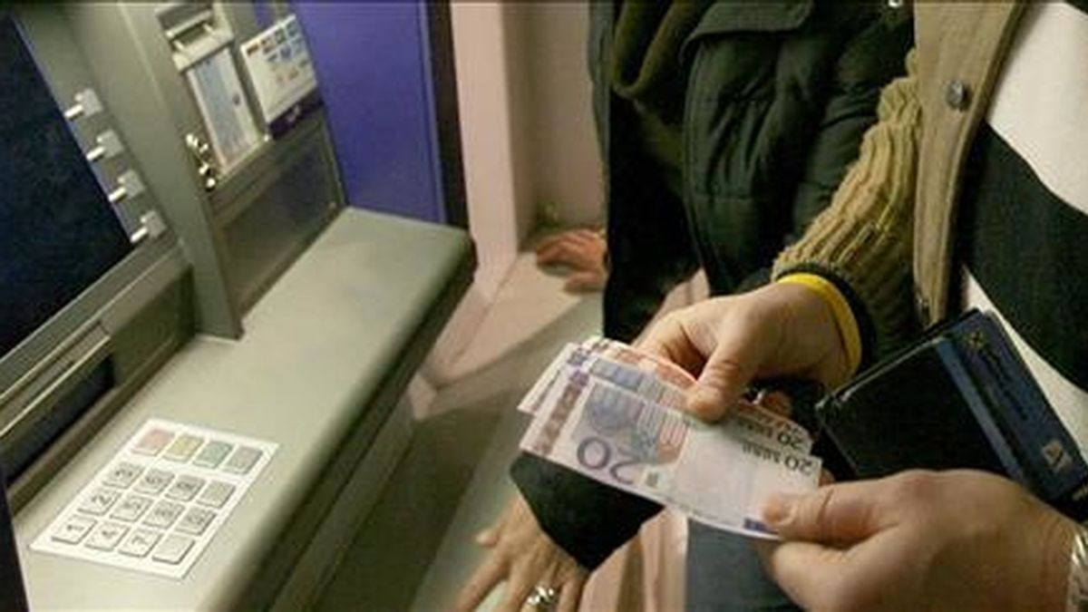 Un hombre observa unos primeros billetes de euros que obtiene de un cajero. EFE/Archivo