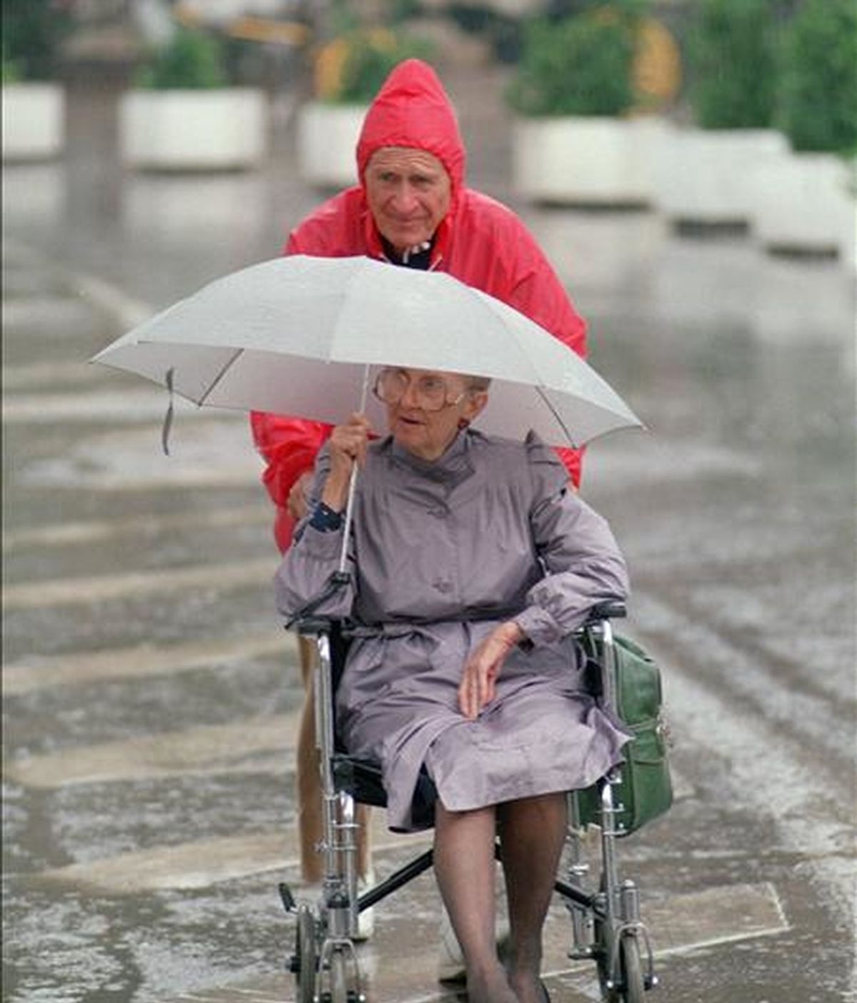 Un hombre arrastra una silla de ruedas llevando a una anciana. EFE/Archivo