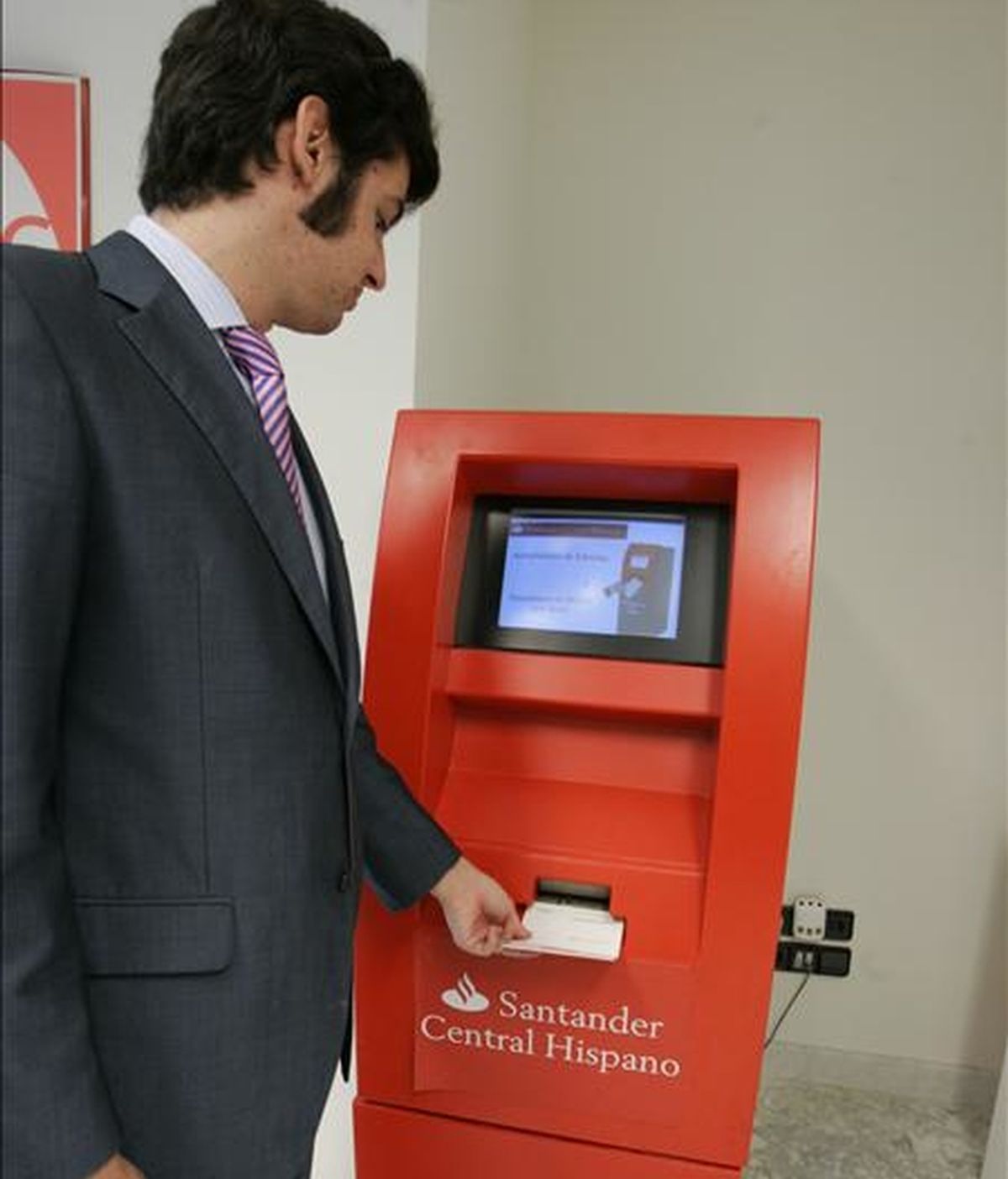 Un cliente actualiza su libreta en un cajero automático de una oficina del Banco Santander. EFE/Archivo