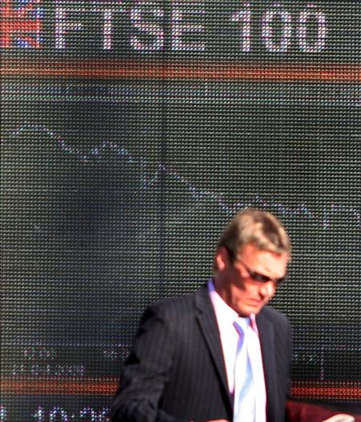 Un hombre pasa por delante de un panel electrónico que muestra el valor de la Bolsa de Londres. EFE/Archivo