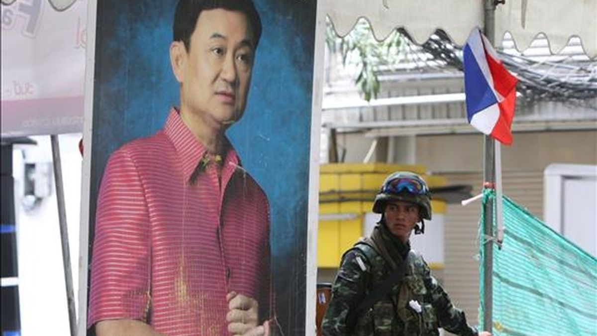 Un soldado es fotografiado junto a una imagen del ex primer ministro tailandés Thaksin Shinawatra donde se lee "por favor confiar en el sistema parlamentario" en el centro de Bangkok (Tailandia), el pasado 20 de mayo. EFE/Archivo