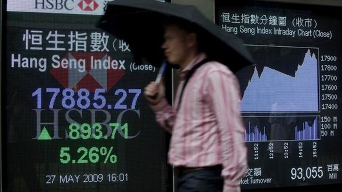 Un hombre pasa por delante de una pantalla en la que se reflejan los valores de la Bolsa, en Hong Kong. EFE