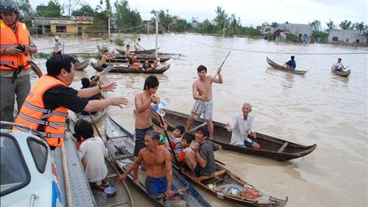 Un grupo de personas utiliza botes para acercarse a los trabajadores municipales que realizan labores de rescate, tras una tormenta tropical en Vietnam. EFE/Archivo