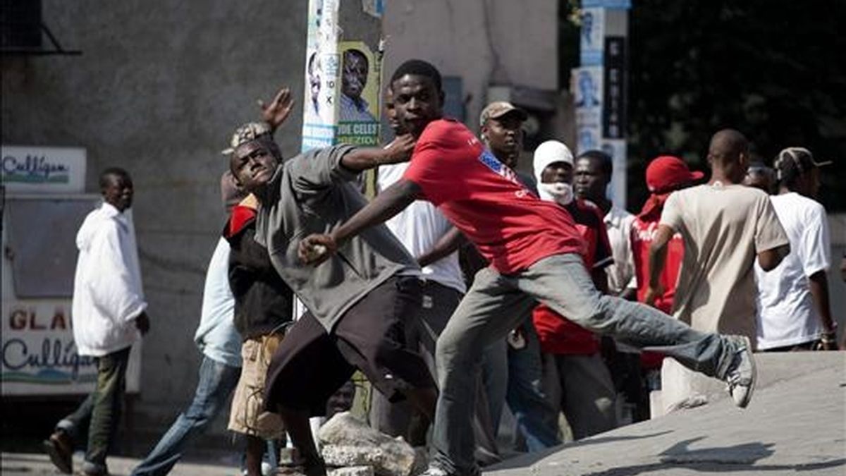 Dos jóvenes arrojan piedras contra un grupo de cascos azules de MINUSTAH que custodian los alrededores del Consejo Electoral Provisional (CEP) en el suburbio de Petion Ville, en Puerto Príncipe (Hiatí). EFE