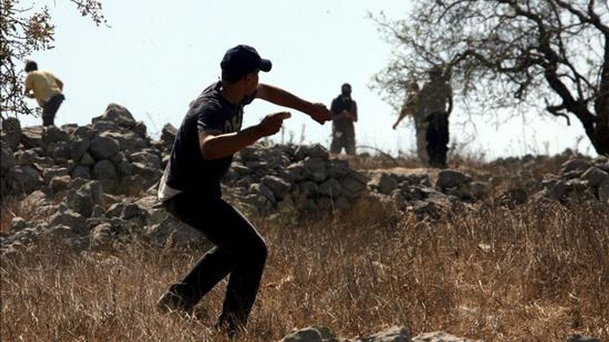 Un joven palestino lanza hoy piedras contra unos colonos israelíes para evitar que éstos ataquen la localidad de Burin cerca de la ciudad cisjordana de Naplusa. Los colonos protestan por el derrumbamiento de casas móviles en el asentamiento cercano de Yitzar. Hay varios heridos por los enfrentamientos en la zona. EFE