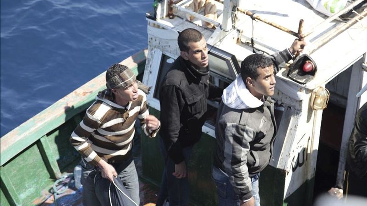 Migrantes norafricanos miran desde uno de los dos botes rescatados por la Guardia Costera en la costa de Lampedusa, Italia. EFE