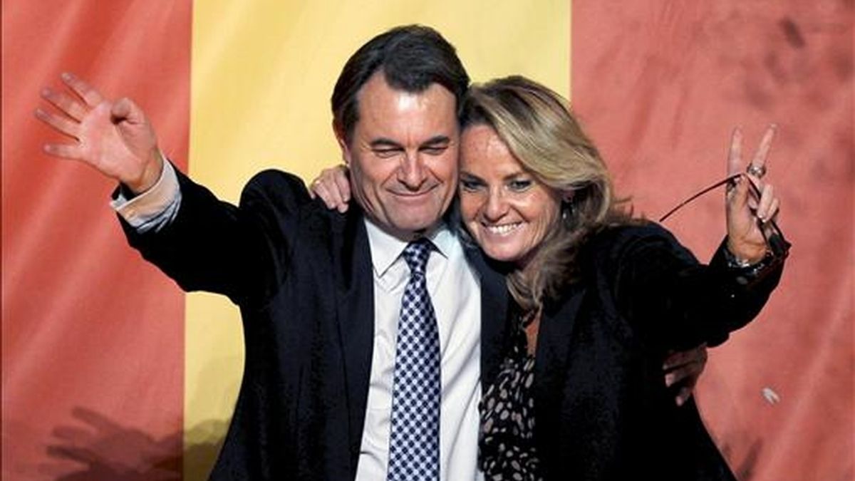 El candidato de CiU, Artur Mas, junto a su mujer, Helena Rakosnik, saludan a sus simpatizantes desde el balcón de un céntrico hotel de Barcelona. EFE