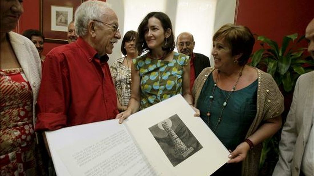 La ministra de Cultura, Ángeles González-Sinde (c), acompañada por el artista Arcadi Blasco (i), y la alcaldesa de Mutxamiel, Asunción Llorens (d), muestra un libro con una de las obras del escultor durante la visita que ha realizado hoy al Ayuntamiento la localidad alicantina para conocer el proyecto museístico "Arcadi Blasco". EFE