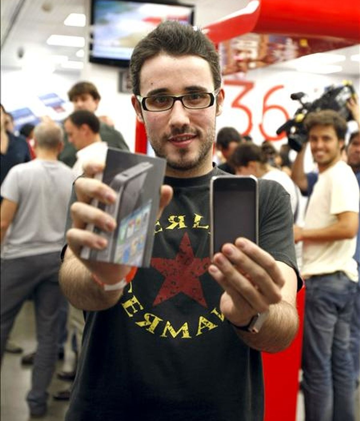 Uno de los primeros compradores del último móvil inteligente de Apple, el iPhone 4, posa con él tras conseguirlo en una de las tiendas que han abierto esta medianoche en Madrid para vender las primeras unidades del nuevo dispositivo. EFE