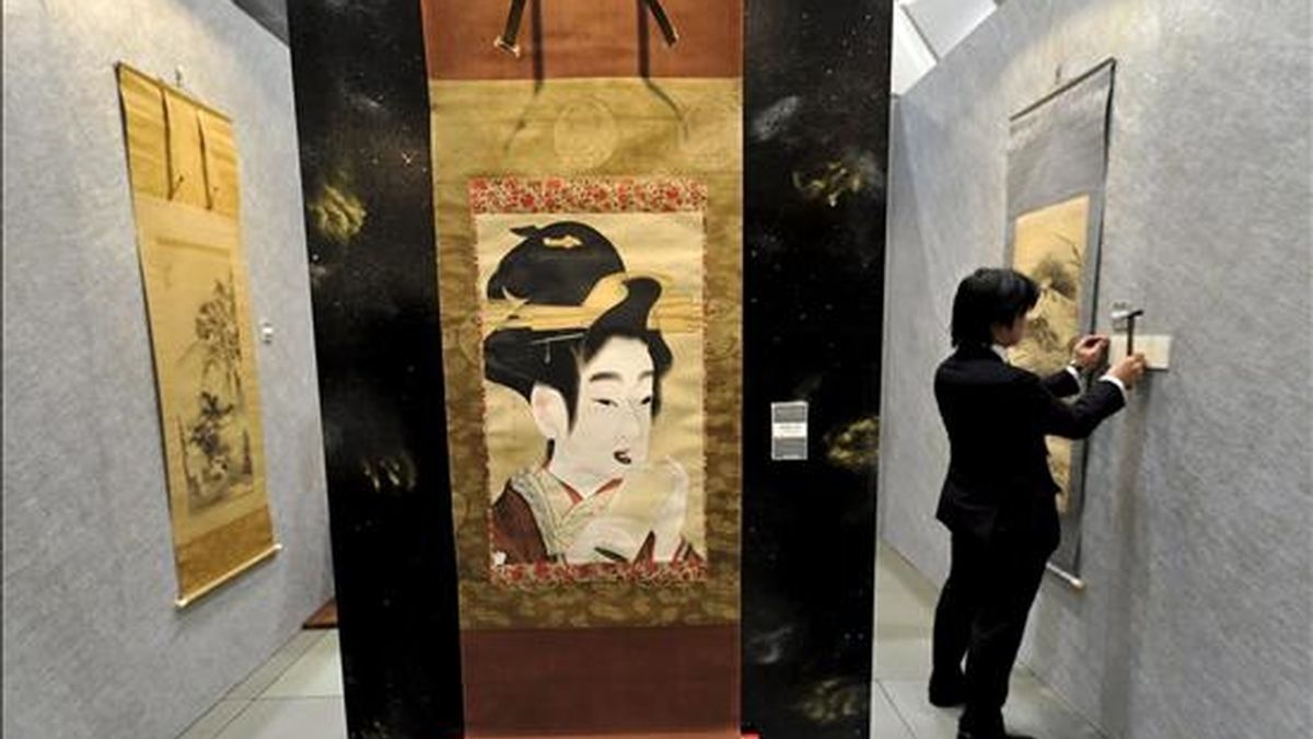 Un empleado coloca una placa junto a una obra del artista japonés Gion Seitoku durante la Feria de Arte de Tokio (Japón), hoy, 2 de abril. Cerca de 150 galerías presentan durante tres días las obras de unos 650 artistas.EFE/Franck Robichon