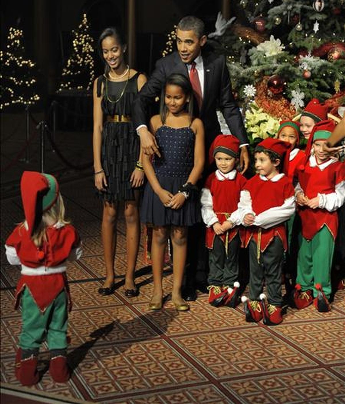 El presidente Obama, y sus hijas Malia (i) y Sasha (2i), posan junto a un grupo de niños, durante la celebración de la fiesta navideña en el Museo Building de la ciudad de Washington D.C (EEUU). EFE