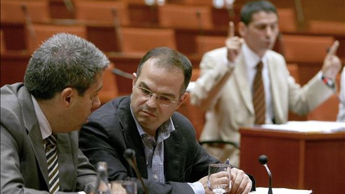 Jordi Turull (c) y Francesc Homs (i), de CiU, hablan mientras Pere Bosch, de Esquerra, interviene en la comisión de investigación sobre las irregularidades detectadas en la gestión del Palau de la Música que hoy ha elaborado el dictamen final para que sea aprobado en el pleno parlamentario de mañana. EFE