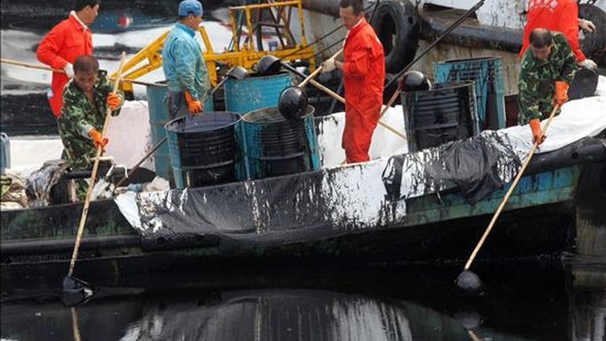 Vista de un grupo de trabajadores que recoge petróleo crudo que flota en el mar cerca a la población china de Dalian en la provincia de Liaoning el domingo 18 de julio de 2010. EFE