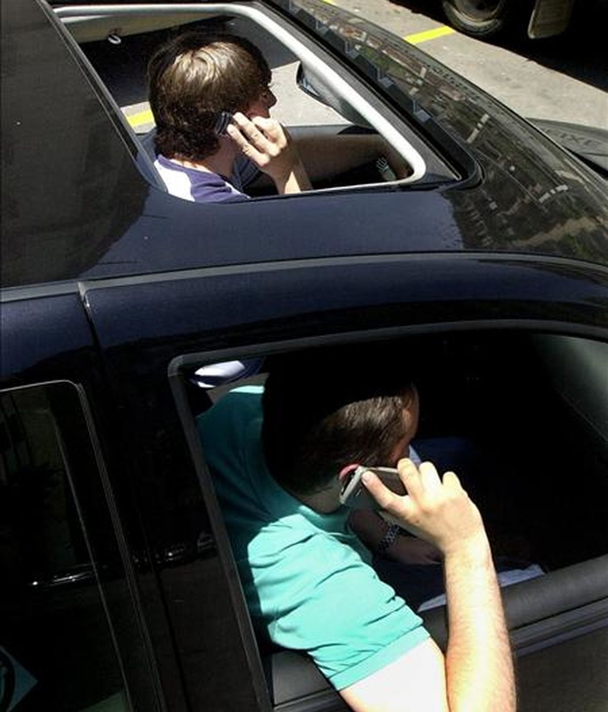 Dos jovenes utilizan sus teléfonos móviles en el interior de un coche en el centro de Barcelona. EFE/Archivo