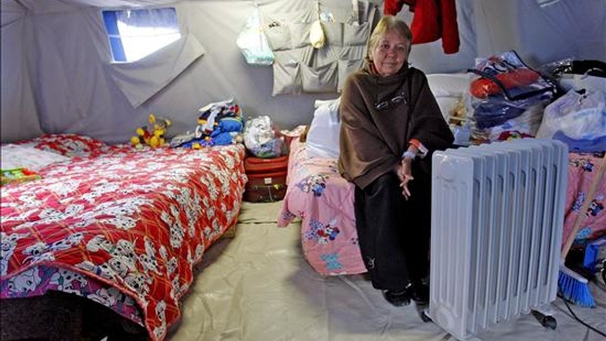 Una mujer trata de calentarse con un calentador eléctrico en su tienda del campamento para damnificados que se ubica en las cercanías de L'Aquila, Italia. EFE
