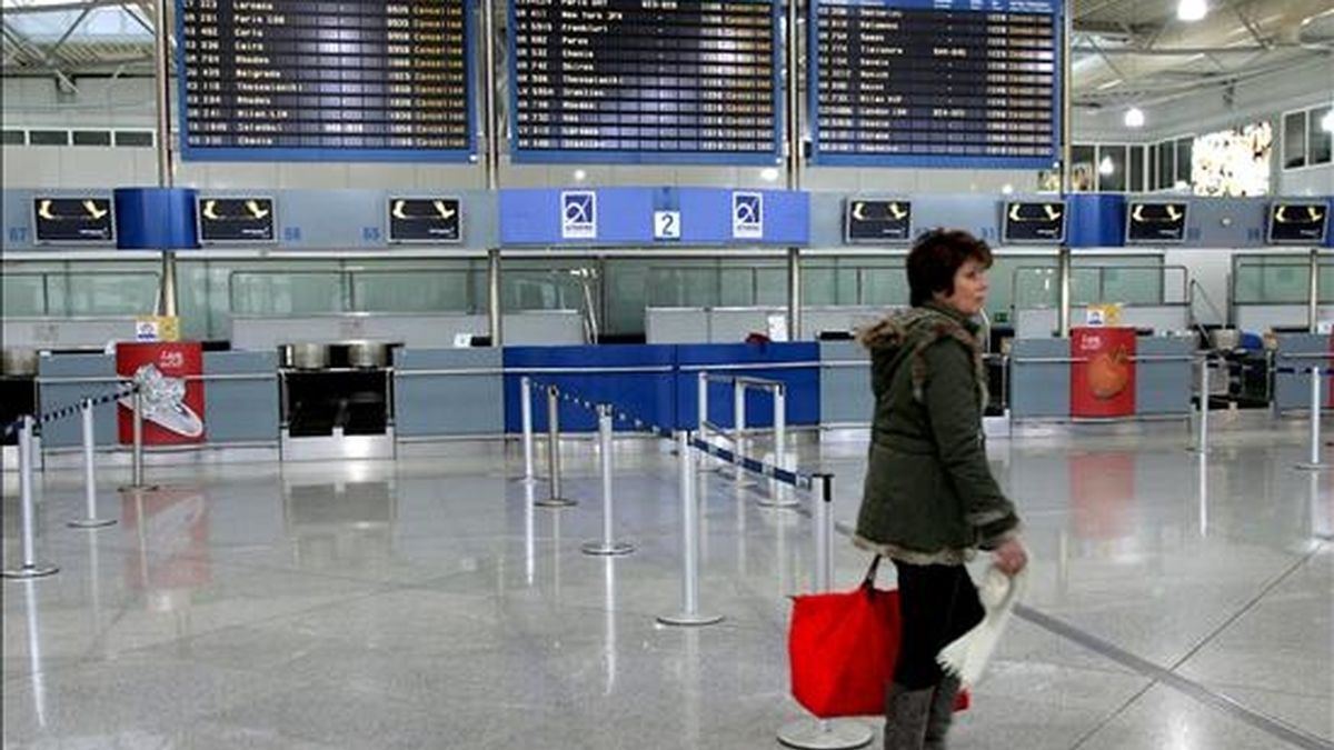 En la imagen, una mujer pasa ante los mostradores vacíos del aeropuerto de Atenas, Grecia.