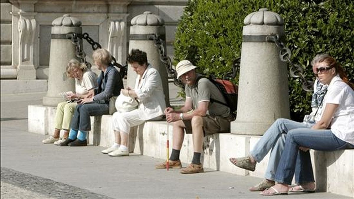 Un grupo de turistas se toman un descanso en su jornada en uno de los accesos a la Catedral de la Almudena, en Madrid. EFE/Archivo
