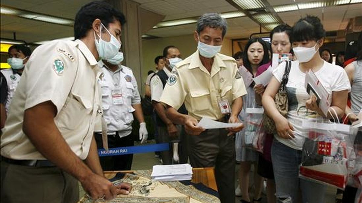 Un grupo de turistas rellena un formulario sobre salud a su llegada al Aeropuerto Internacional de Ngurah Rai en Bali (Indonesia), el 25 de junio de 2009. EFE