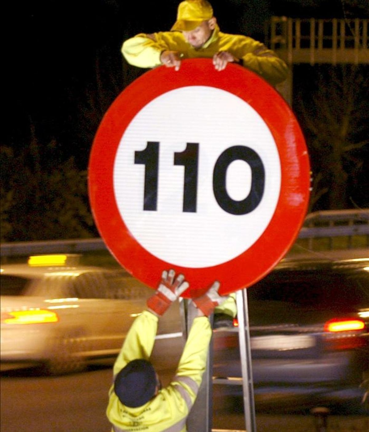 Varios operarios colocan el límite de velocidad de 110 kilómetros/hora en una señal de la A-2 situada en el kilómetro 6, en Madrid. EFE/Archivo