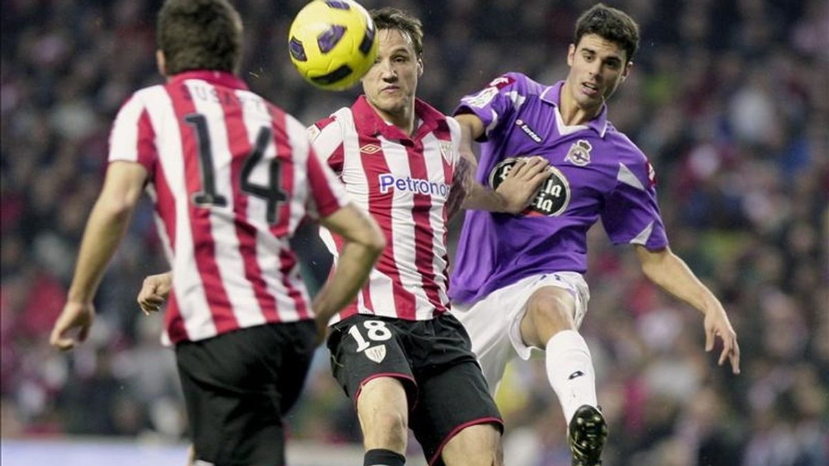 El centrocampista del Athletic Club de Bilbao Carlos Gurpegi (c) se adelanta en la jugada al centrocampista del Deportivo Juan Domínguez (d) ante la mirada del centrocampista del Athletic Markel Susaeta (i) durante un partido. EFE/Archivo