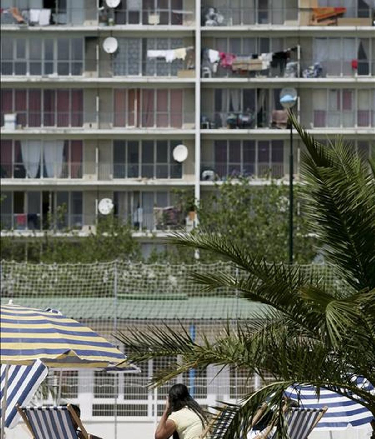 Un grupo de residentes toma el sol en una playa con un conjunto de apartamentos al fondo. EFE/Archivo
