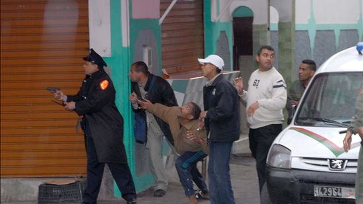 En la imagen, un policia marroquí empuña una pistola frente a la casa donde un hombre fue detenido tras amenazar con hacer estallar un artefacto en el barrio Al Farah de Casablanca, Marruecos. EFE/Archivo