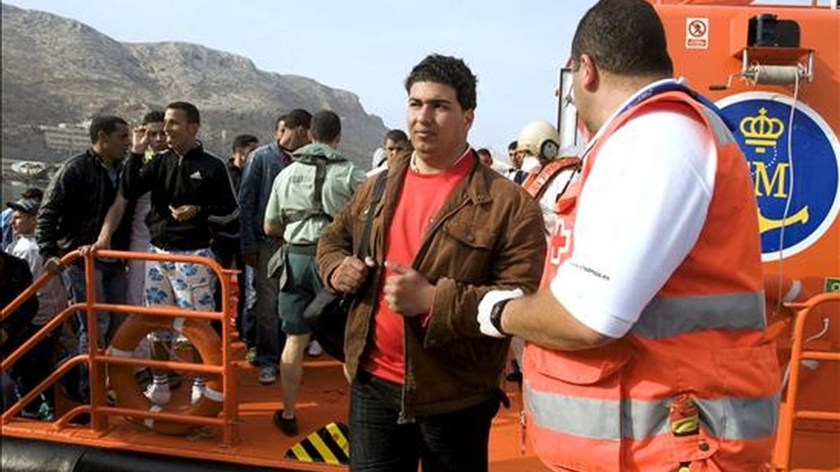 Un inmigrante es acompañado por un miembro de la Cruz Roja a su llegada al puerto de Almería. EFE/Archivo