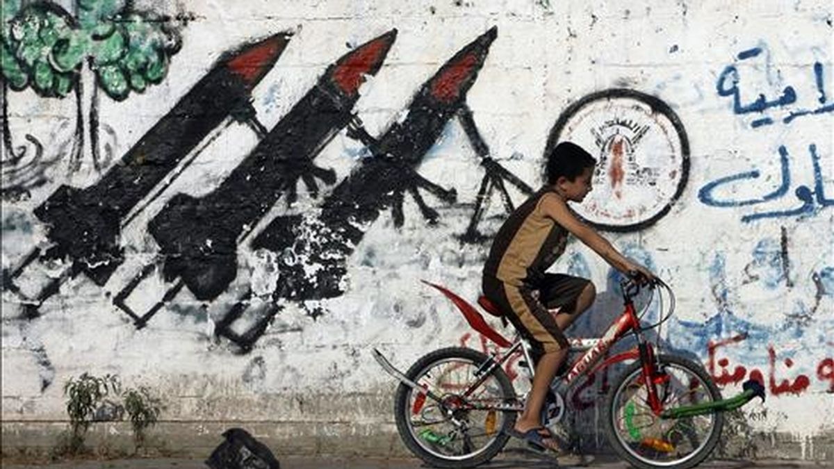 Un niño palestino monta su bicicleta frente a un muro que presenta algunas pintadas de cohetes de Hamás en las calles del campo de refugiados de Jabaliya en el norte de la Franja de Gaza. EFE/Archivo