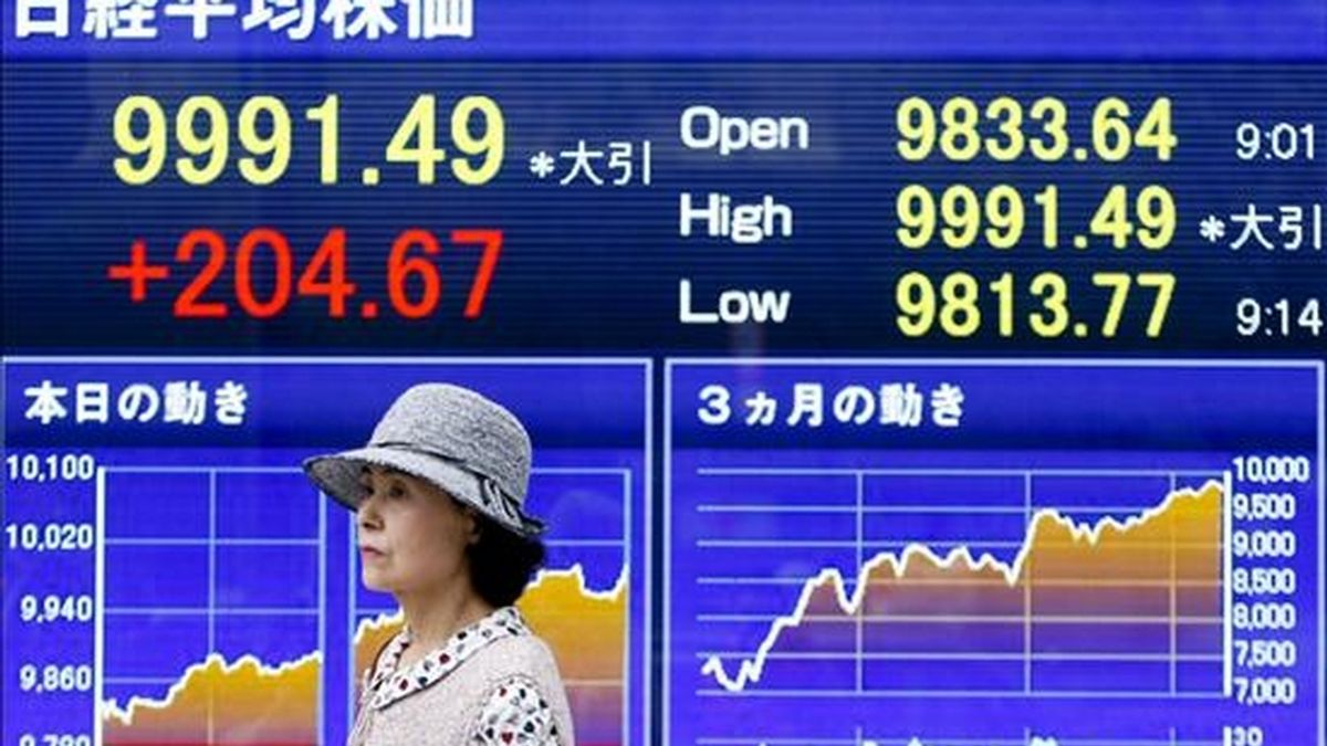 Una mujer pasa por delante de una pantalla en la que se muestran los precios de las acciones, en Tokio (Japón). EFE/Archivo