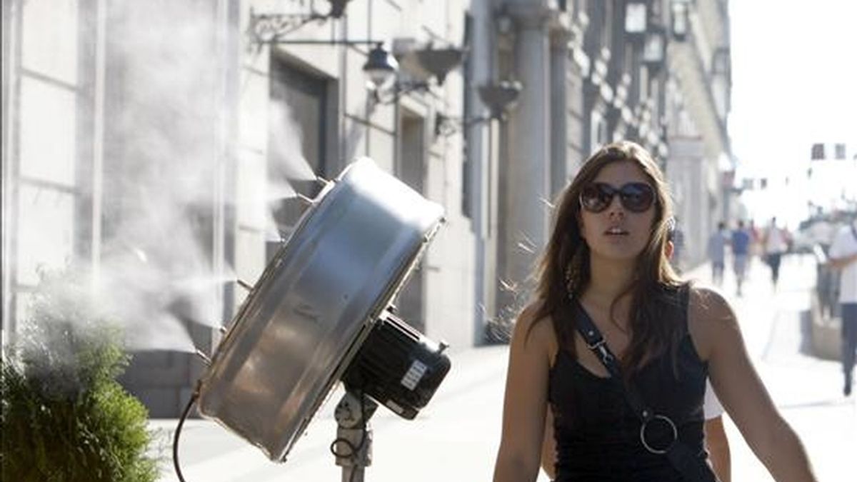 Una joven posa junto a un ventilador de agua pulverizada en la calle de Alcalá, en Madrid. EFE/Archivo