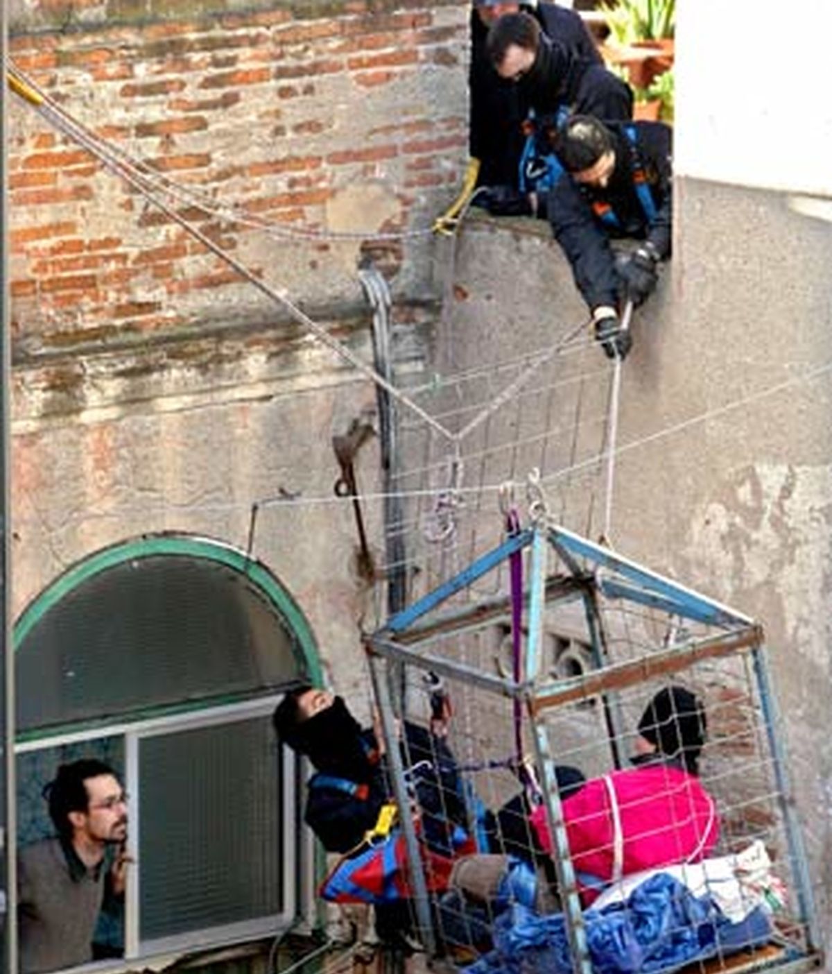 Varios mossos d'esquadra tratan de soltar a un joven que se ha encerrado en un jaula colgada en el patio interior. Foto: EFE.