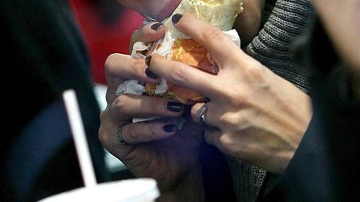 Una mujer come una hamburguesa en un restaurante. EFE/Archivo