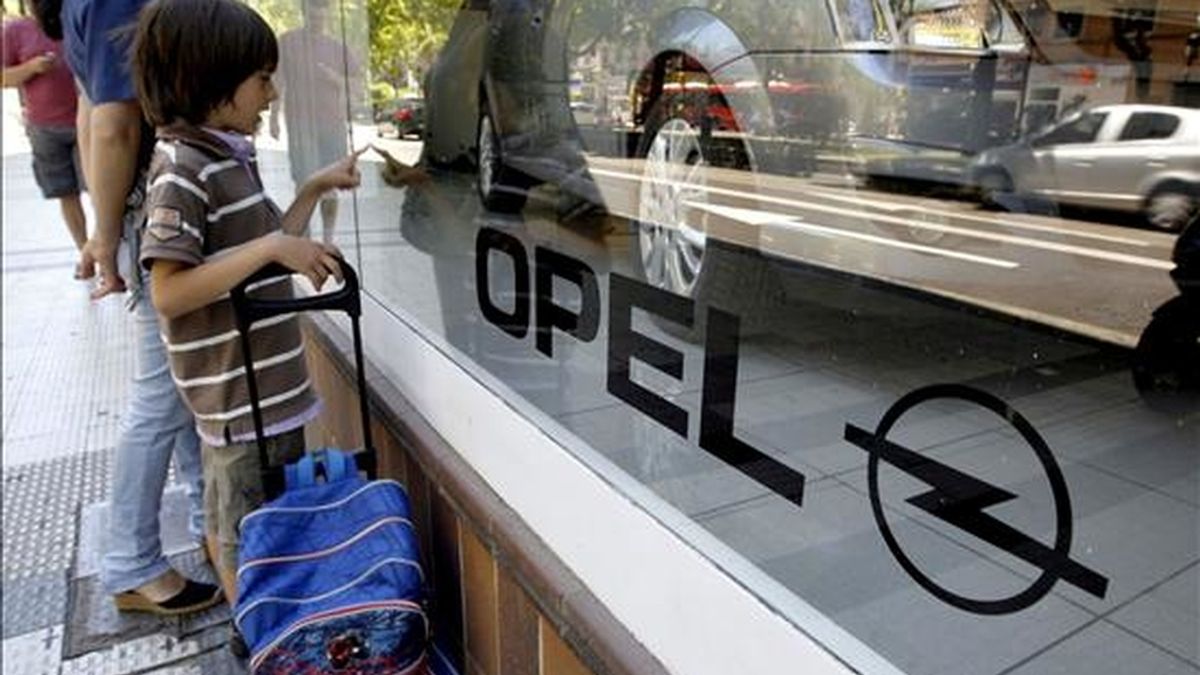 Un niño contempla un coche en el escaparate de un concesionario de la marca Opel (General Motors). EFE/Archivo