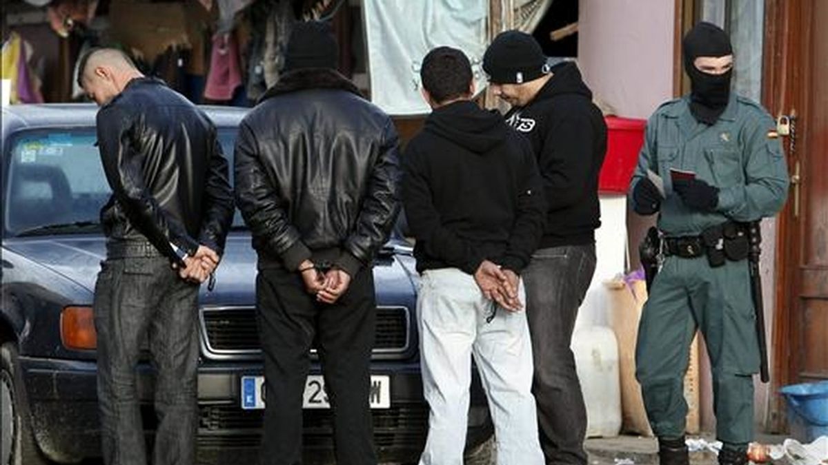 Un agente custodia a varios detenidos durante la macrooperación que la Guardia Civil llevó a cabo ayer en relación con el robo de cobre en el núcleo chabolista de "El gallinero", junto a la Cañada Real, al sur de la ciudad de Madrid. EFE