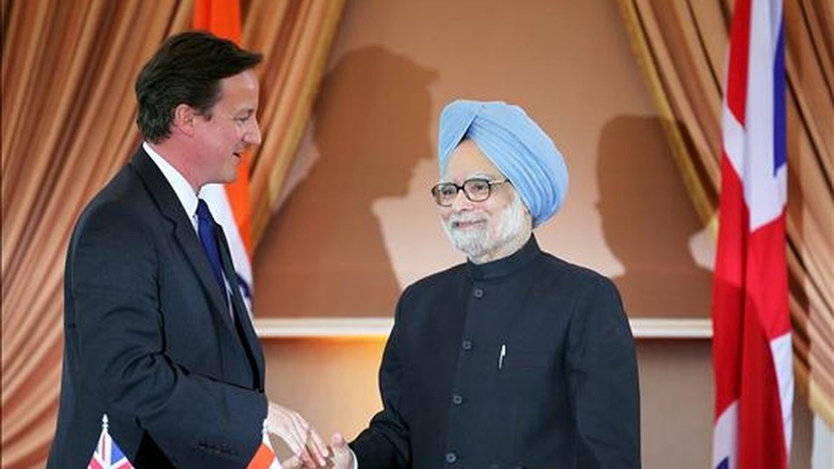 El primer ministro británico, David Cameron (i), estrechando la mano de su homólogo indio, Manmohan Singh, después de la rueda de prensa que ofrecieron en Nueva Delhi este jueves. EFE