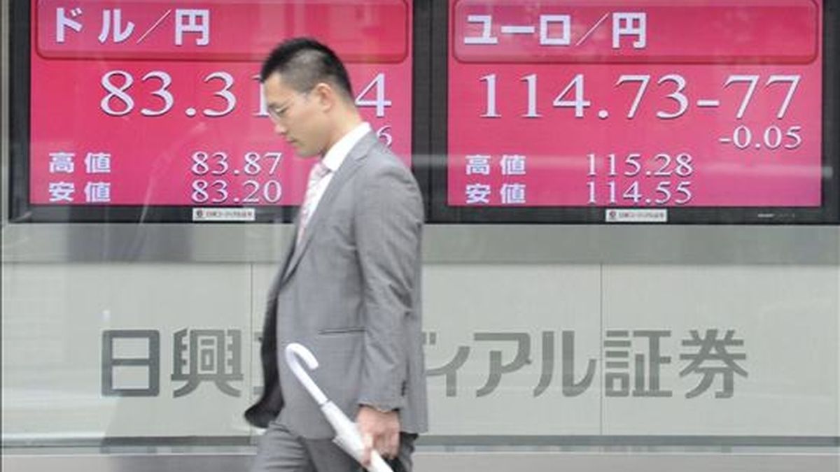 Un hombre de negocios camina junto a unas pantallas que ofrecen la informaciónn bursátil en el centro de Tokio (Japón). EFE/Archivo