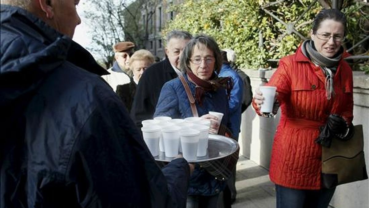 Los ciudadanos que hacen cola para visitar hoy el Senado, en el primer día de la XIII Jornada de Puertas Abiertas que concluye el próximo viernes, toman una taza de caldo para contrarrestar el frío. EFE