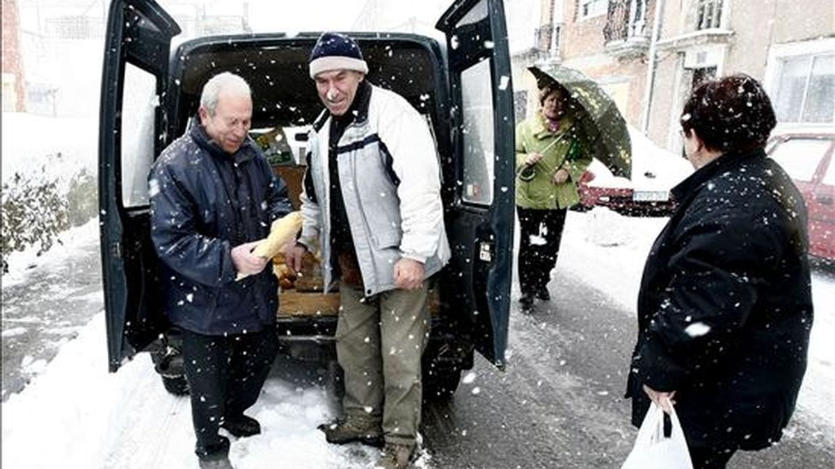Vecinos de la localidad de Matamorosa se acercan al repartidor del pan en medio de una nevada el pasado sábado en Cantabria. EFE