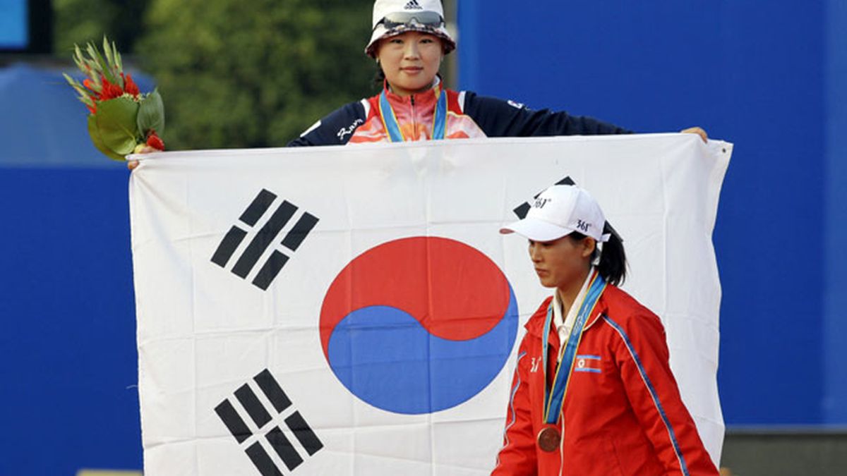 La deportista surcoreana alza la bandera al paso de la de Corea del Norte. FOTO: AP.