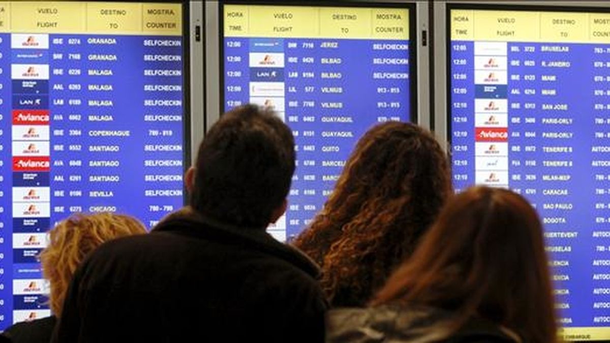 Varias personas consultan en un panel informativo el estado de sus vuelos, en el T-4 del aeropuerto de Barajas, en Madrid. EFE/Archivo