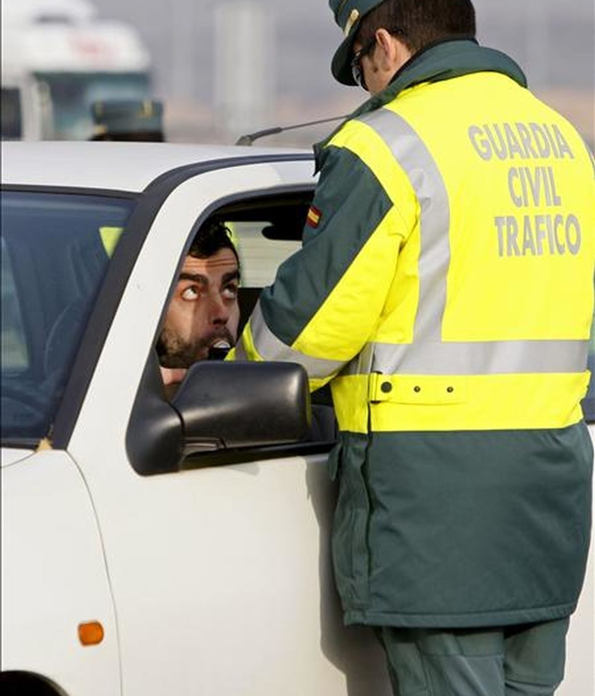 Un conductor realiza una prueba de alcoholemia a instancias de un guardia civil de tráfico en un control situado en el kilómetro 14 de la Nacional III, dentro de la campaña de Navidad puesta hoy en marcha por la DGT. EFE