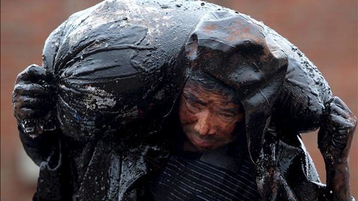 Una fotografía facilitada el pasado 22 de julio que muestra a un hombre mientras trabaja en la limpieza de la playa contaminada por crudo en Dalian, noreste de China, el 21 de julio. La explosión de un oleoducto cercano al puerto provoó el derrame de más de 1.500 toneladas de crudo. EFE/Archivo