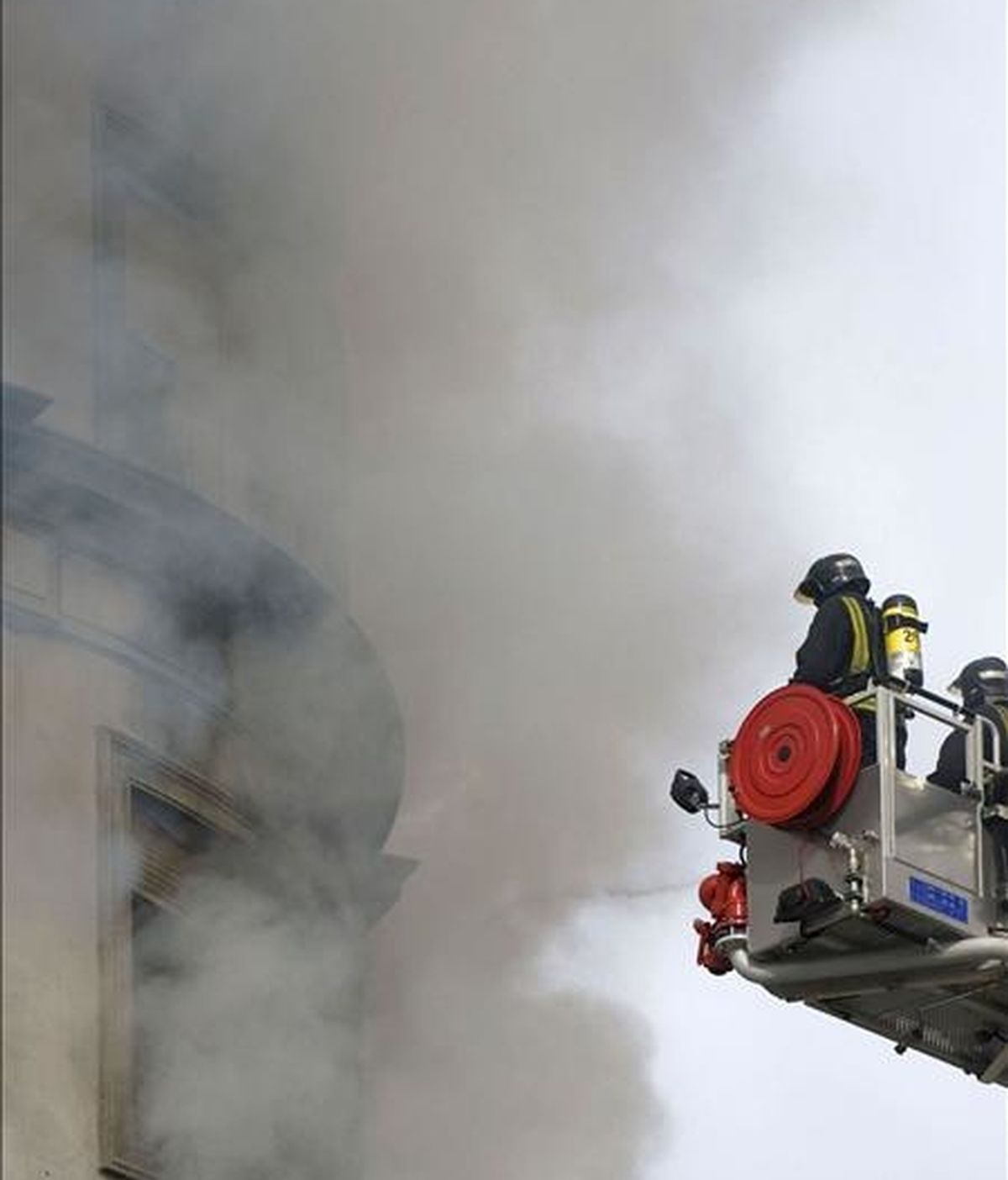 Unos bomberos trabajan en el control y extinción del incendio que se ha declarado esta mañana por causas desconocidas en una vivienda situada en la esquina de la plaza de América de Valencia con la calle de Cirilo Amorós. EFE