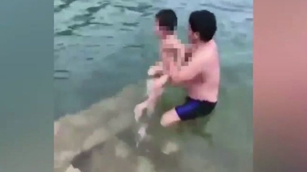 Un padre lanza a su hijo desnudo a un lago para que este aprenda a nadar