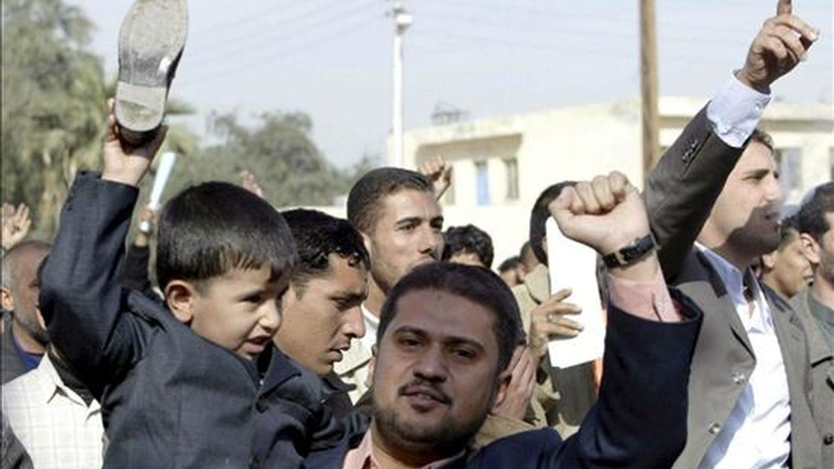 Un niño iraquí sostiene un zapato durante un acto en apoyo a Montazer al Zaidi en Basora, Irak. EFE/Archivo