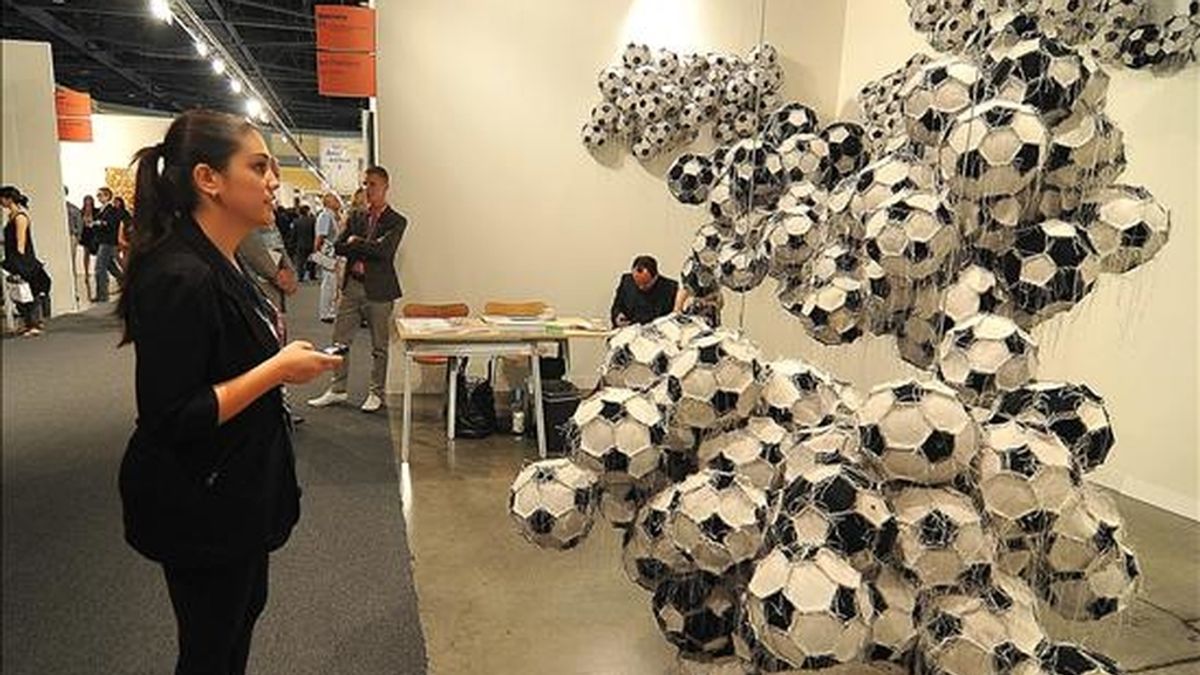 Una mujer observa la instalación conceptual "Obverse & Reverse" del guatemalteco Darío Escobar, hecha a base de pelotas de fútbol cosidas unas con otras durante un previo a la inaguración de la prestigiosa Art Basel Miami Beach. EFE/Archivo